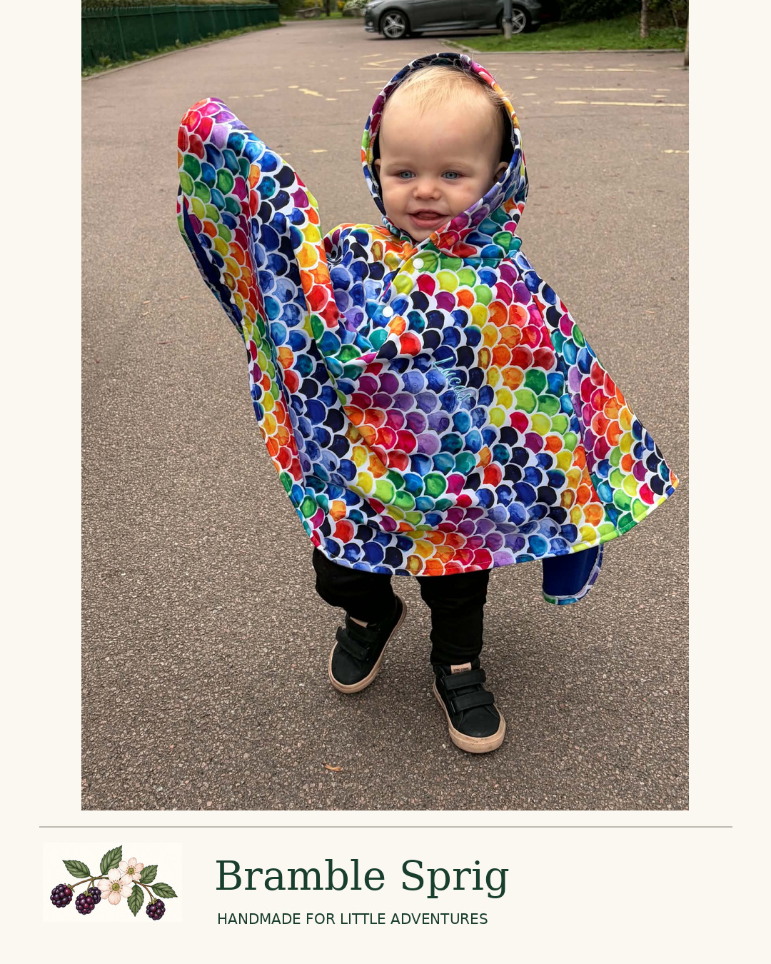 Child wearing a colourful Bramble Sprig rainbow poncho outdoors